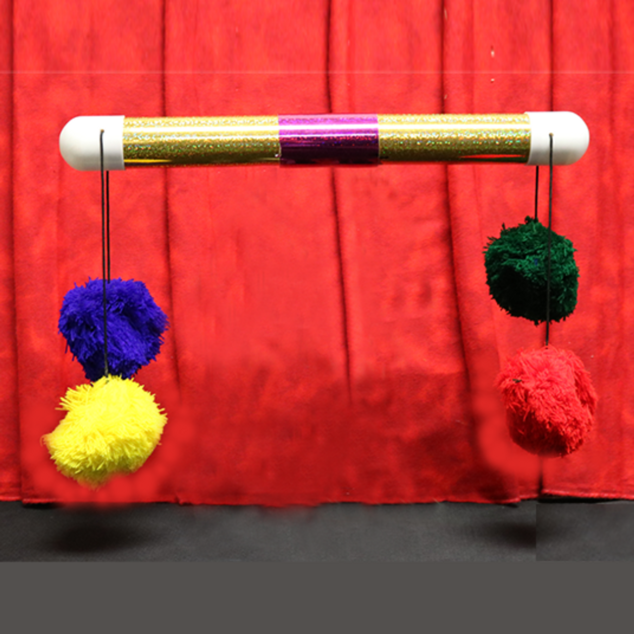 image of a long thin glittery golden tube with a connector in the middle, allowing it to pull apart. Both ends of the tube have two pieces of string hanging out, with a different coloured pom pom at the end of each.