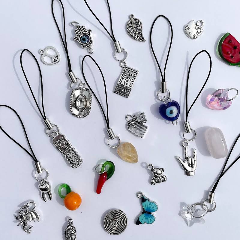 An array of different phone charms, with little cord loops on them.